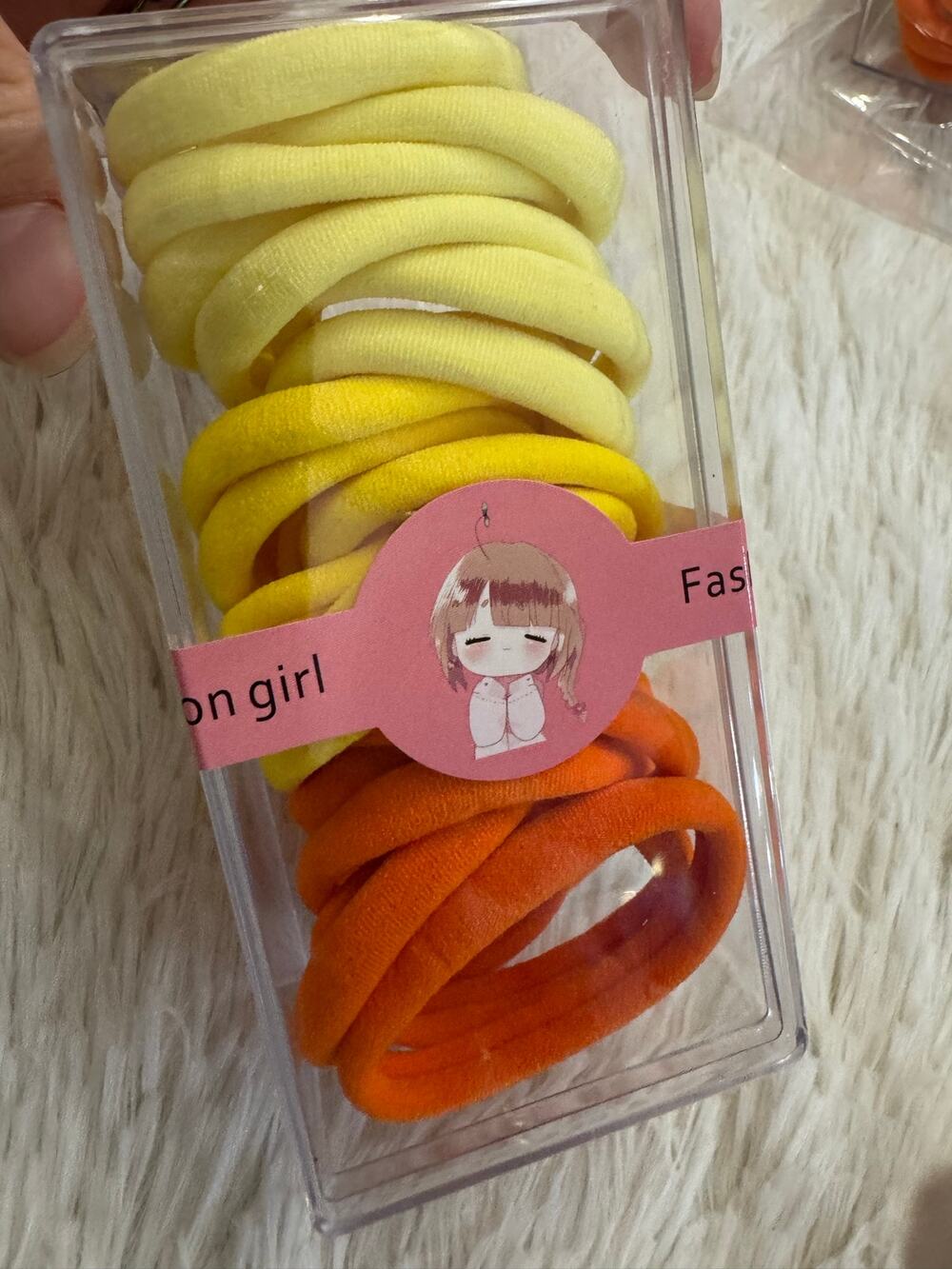Yellow and orange hair ties in a clear box on 3 tones  ready for school